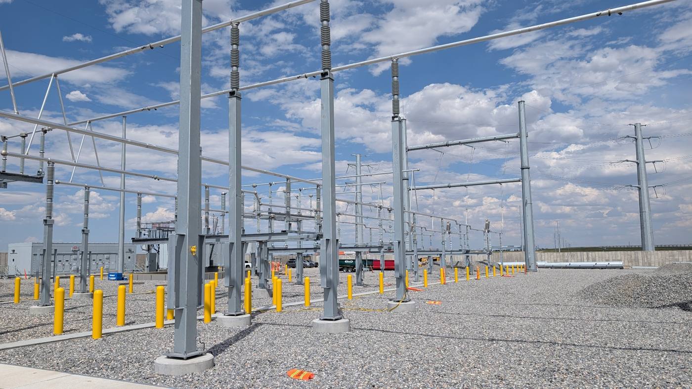 New substation with steel structures, insulators, and yellow safety bollards